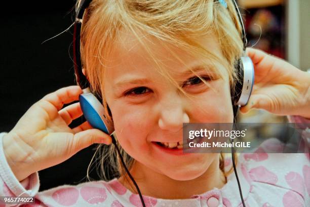 Petite fille de six ans ecoutant de la musique avec un casque.