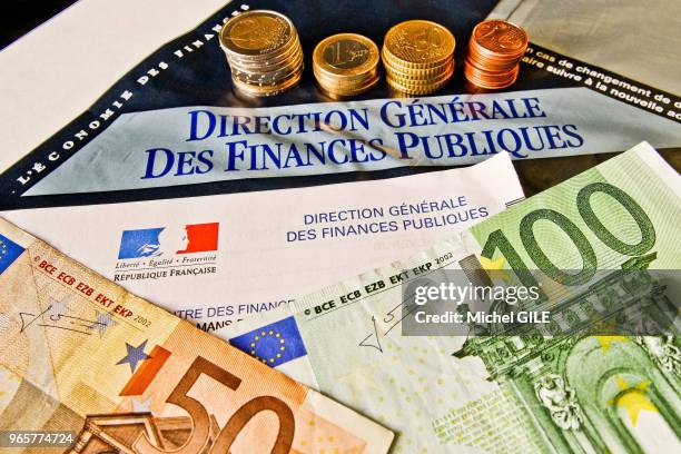 Feuille d'impôt de la direction générale des finances publiques, diverses pièces en euros et des billets de banque de 100 et 50 euros.