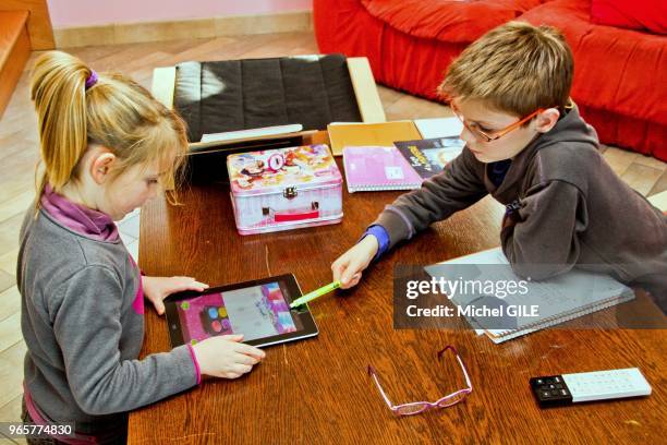 Petite fille de six ans et petit garçon de 9 ans jouant avec une tablette numérique.