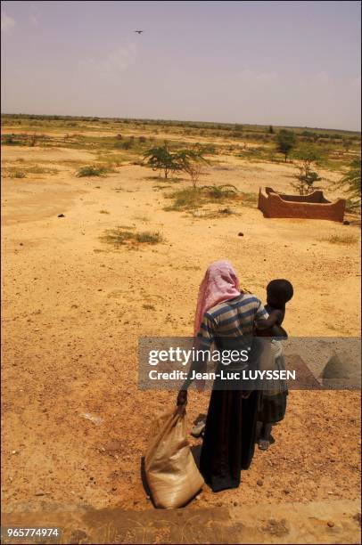 Womand and her child leaving the Crenam of Sabin Kafi in the region of Zinder with two weeks worth of food rations.