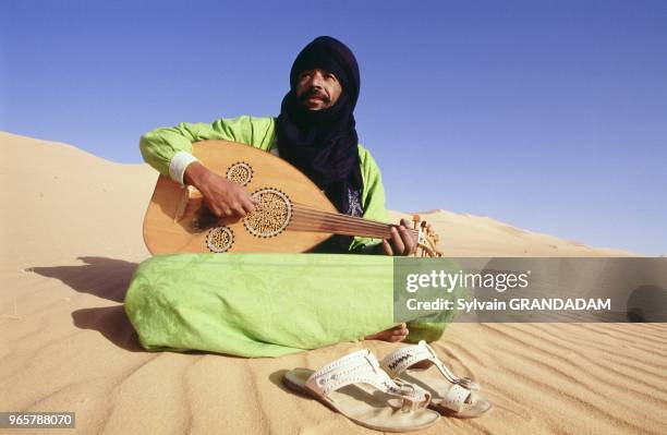 BALY, CHANTEUR ET MUSICIEN TOUAREG, SUR UNE DUNE DE SABLE DE L'ERG ADMER, TASSILI N'AJJER, DESERT DU SAHARA, ALGERIE.