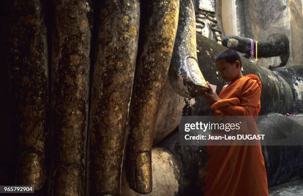 Ancienne capitale du royaume de Siam. Temple de Si-Chum. Sanctuaire abritant une statue de Bouddha assis haute de 15 mètres.Un jeune novice...