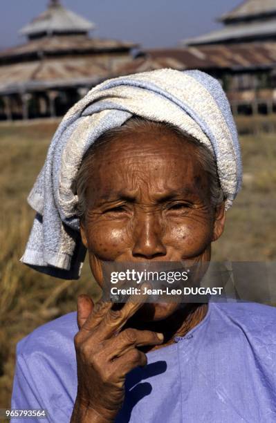 Village de Nyaungshwe. Vieille femme tirant sur son cheroot, le cigare birman fait de tabac enroulé dans une feuille. Village de Nyaungshwe. Vieille...