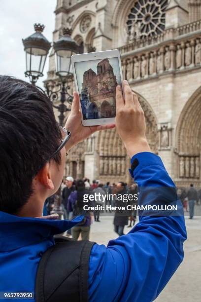 Touriste photographiant les portails de Notre Dame, Paris.