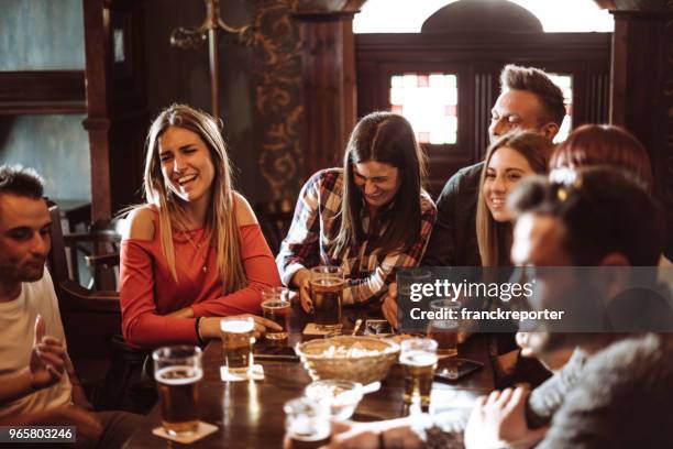 mensen praten binnenshuis in een pub met de bieren - happy hour stockfoto's en -beelden