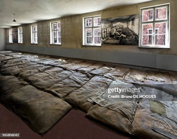 Des matelas en paille recouverts de toiles de sacs où dormaient les prisonniers. Une aquarelle de Jerzy Potrzebowski montrant un Kapo donnant un coup...