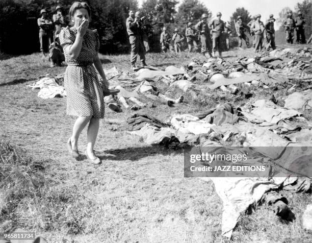 German girl is overcome as she walks past the exhumed bodies of some of the 800 slave workers murdered by SS guards near Namering, Germany, and laid...