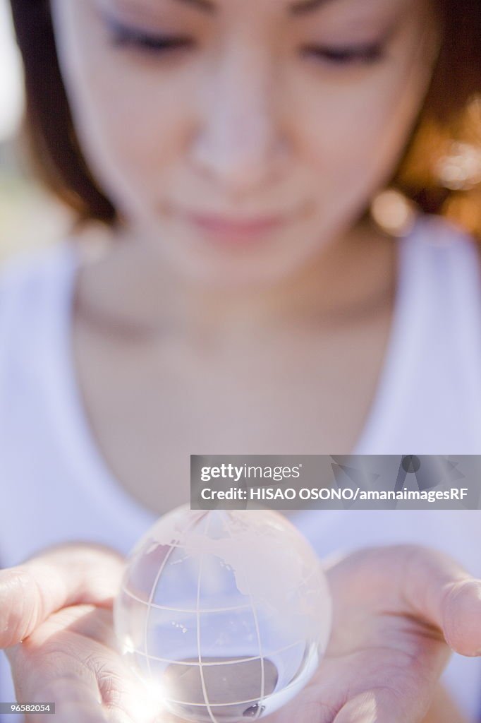 Young woman holding globe in hands, close up