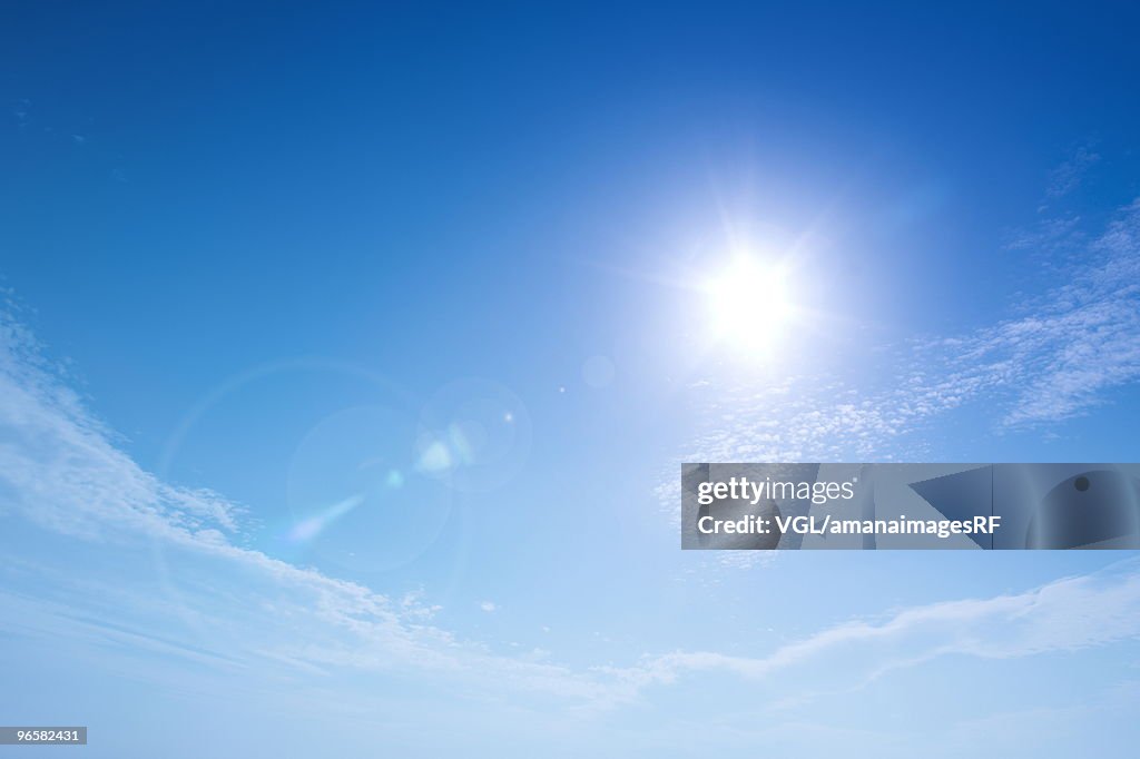 Sun and clouds in blue sky, lens flare, copy space