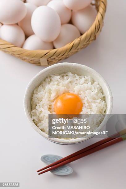 row egg on bowl of rice, white background - egg white background stock-fotos und bilder