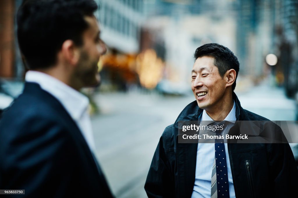 Smiling business colleagues in discussion while standing on city street
