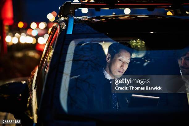 businessman showing colleague data on digital tablet while sitting in car - indian ethnicity car stock pictures, royalty-free photos & images