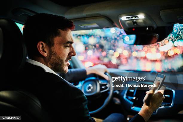 businessman looking at smartphone in car before departing on evening commute - cellphone car stock pictures, royalty-free photos & images