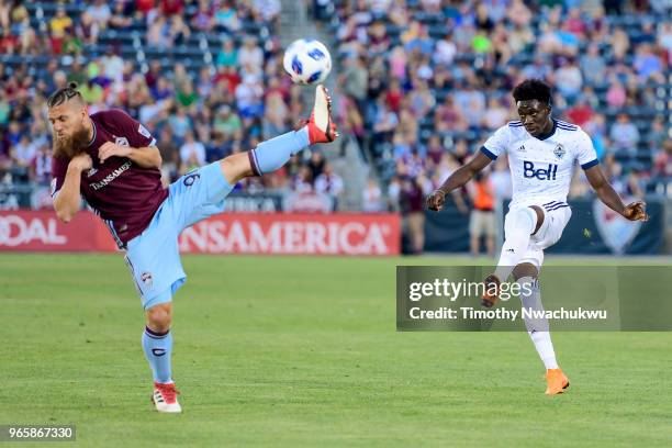 Alphonso Davies of Vancouver Whitecaps attempts a pass over Enzo Martinez of Colorado Rapids at Dick's Sporting Goods Park on June 1, 2018 in...