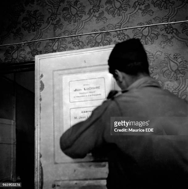 Soldier of the 1st French Army removing the label to the office of the collaborator Jean LUCHAIRE - the General Commissioner for Information and...