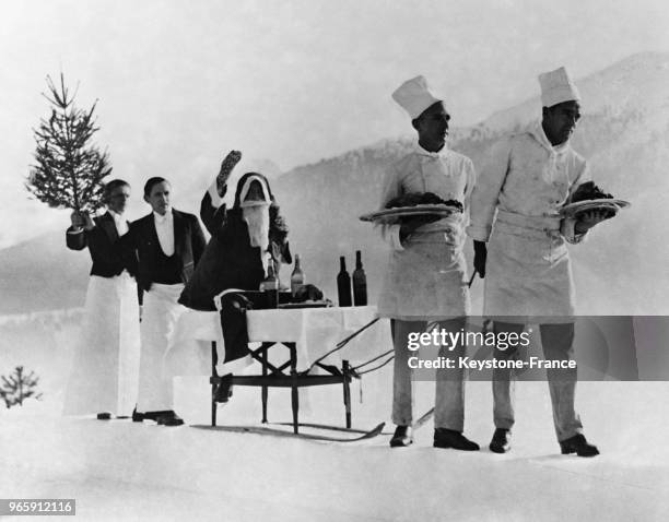 Un cortège formé par deux cuisiniers et deux garçons de café escortant le Père Noël à son arrivée à Saint-Moritz, Suisse le 25 décembre 1932.