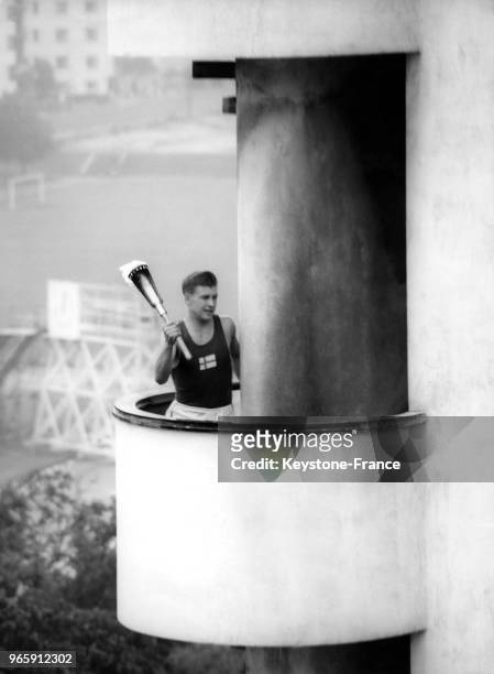 Un athlète finlandais porte la flamme olympique sur la tour du stade lors de la cérémonie d'ouverture des JO le 19 juillet 1952 à Helsinki, Finlande.