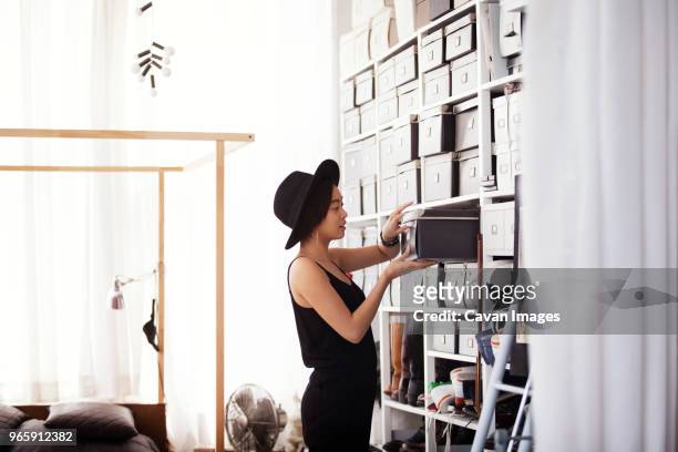 woman searching in box by shelves in bedroom - arrangement stock pictures, royalty-free photos & images