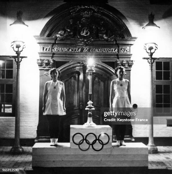 Deux jeunes femmes montent la garde près de la flamme olympique qui est exposée devant l'hôtel de ville pendant la nuit durant son voyage jusqu'en...
