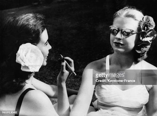 Patricia Moon utilisant les lunettes de soleil de son amie Ruth Evanoff comme miroir pour se maquiller au Maumee River Yacht Club à Toledo, Ohio, aux...