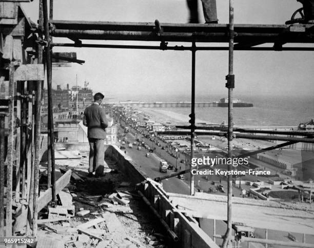 Un homme observe l'avancée des travaux sur le chantier de construction d'un immeuble d'habitation sur le front de mer le 15 mai 1935 à Brighton,...