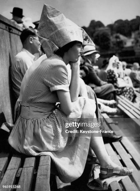 Une jeune femme dans les gradins s'est confectionné un chapeau en papier journal pour protéger sa tête du soleil pendant le match de tennis e 28 juin...