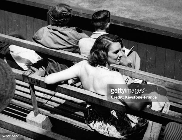 Une jeune femme avec une robe dos-nu assiste à un match de tennis sous la chaleur le 28 juin 1949 à Wimbledon, Royaume-Uni.