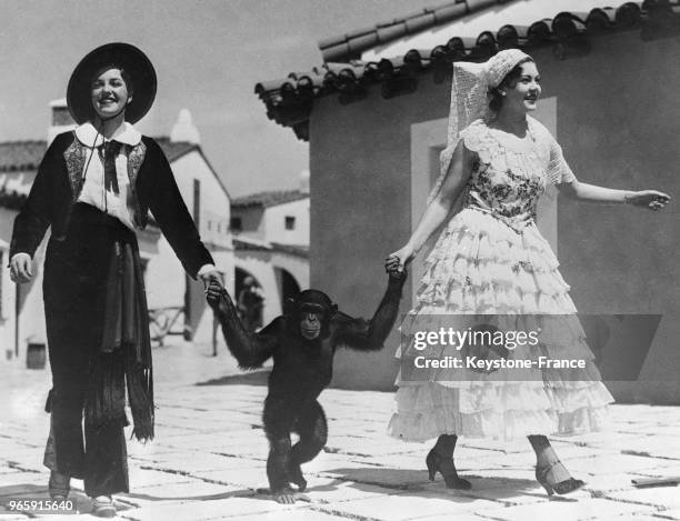 Duke of Wellington', un chimpanzé, mascotte de la Foire-Exposition de San Diego se promène tenant les mains de deux jeunes femmes, à San Diego,...