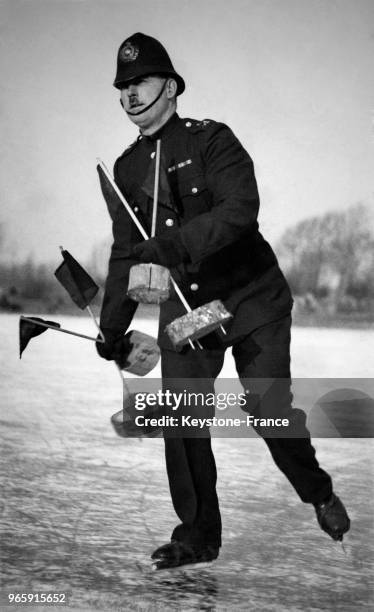 Un policier en patin à glace installe les marques sur la patinoire avant le début du championnat, à Cambridge, Royaume-Uni le 27 janvier 1933.