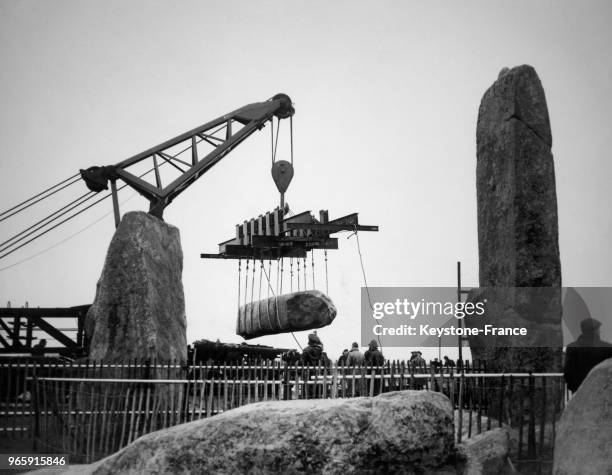 Une grue soulève une partie de la strucutre du monument mégalithique pendant les travaux de rénovation, à Stonehenge, Royaume-Uni le 28 mars 1958.