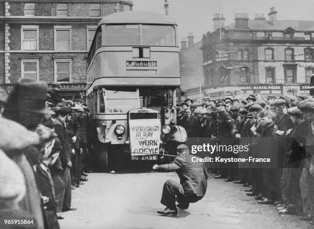 Wilfred Briton faisant une démonstration pendant laquelle il tire un énorme autobus avec ses dents, à Birkenhead, Royaume-Uni le 18 mai 1935.