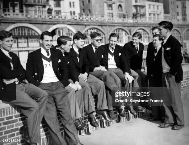 Les étudiants, membres de l'équipe d'aviron d'Oxford, se reposent sur un muret au soleil en bord de mer en prévision de la célèbre course d'aviron...