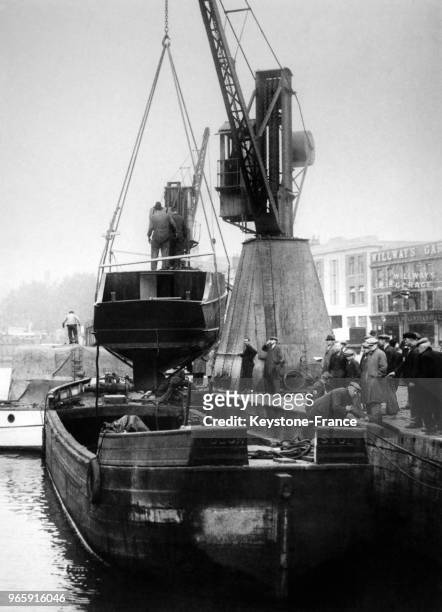 Un bateau débarqué d'une péniche par une grue dans le port le 31 octobre 1934 à Bristol, Royaume-Uni.
