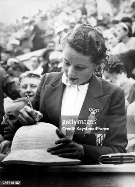 Une joueuse de polo américaine ayant remporté la médaille d'argent appose son autographe sur un chapeau aux Jeux Olympiques le 13 août 1936 à Berlin,...