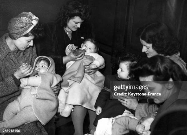 Des femmes de GI américains donnent le biberon à leurs jeunes enfants dans le train qui les conduit au dépôt militaire avant de rentrer aux...