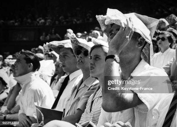 Les spectateurs d'un match de foot se couvrent la tête avec des chapeaux faits de papier journal pendant une vague de chaleur le 28 juin 1949 à...