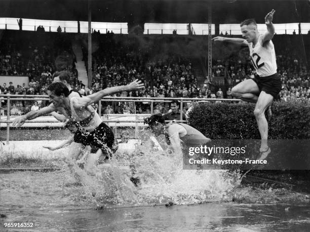 Des coureurs passant l'obstacle de la rivière dans le 3000 m steeple au stade White City à Londres, Royaume-Uni le 19 juillet 1947.