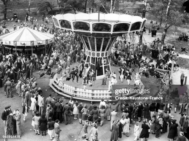 Foule devant un manège à la fête foraine de Hampstead Heath, à Londres, Royaume-Uni le 20 avril 1946.