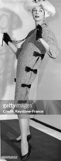 Mannequin présentant un modèle Hale Ludlow: une robe fourreau noire portée sur une tunique de laine noire et blanche garnie de noeuds de satin noir,...