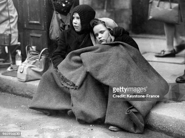 Deux enfants enveloppés dans une couverture devant la cathédrale St Paul à Londres, Royaume-Uni le 26 avril 1948.