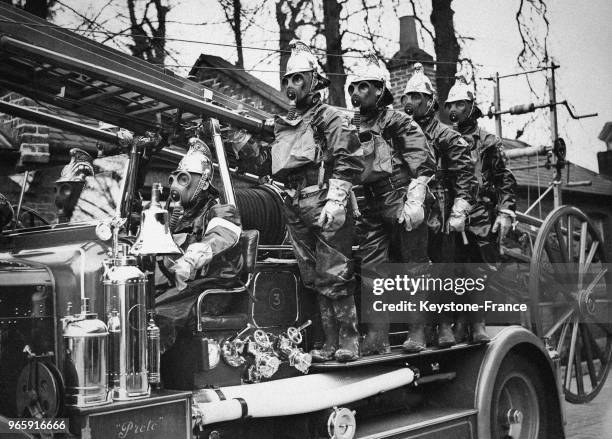 Pompiers de la 'Air Raid Precautions', vêtus de combinaisons de protection et portant un masque à gaz sur le camion défilent dans les rues de...