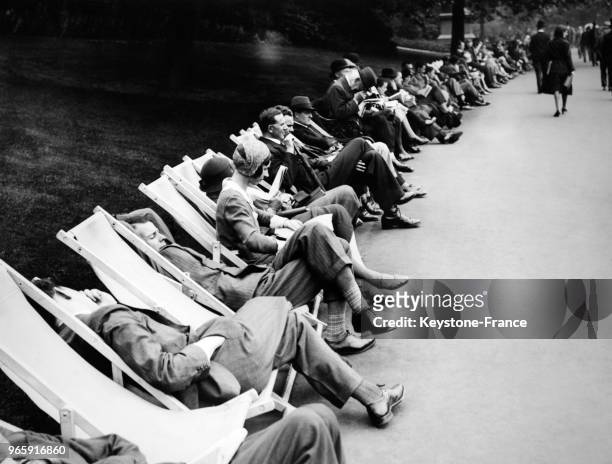 Les travailleurs profitent de leur pause déjeuner pour se reposer sur des transats à l'Embankment Garden à Londres, Royaume-Uni le 13 juin 1932.