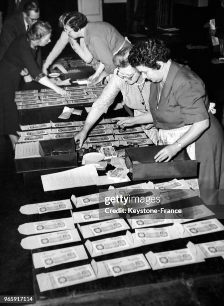 Des femmes en tablier trient les liasses de billets de banque destinés à être répartis équitablement et distribués comme argent de Noël au...