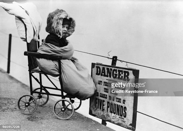 Un enfant, emmitouflé dans sa poussette, fait une promenade dans un parc londonien malgré le froid, à Londres, Royaume-Uni le 25 janvier 1933.