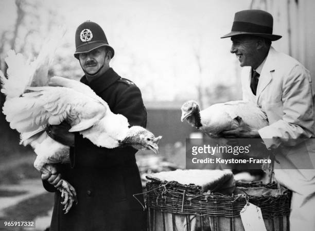 Un policier aide un homme à porter les dindes pour être présentées au salon, à Londres, Royaume-Uni le 14 novembre 1933.