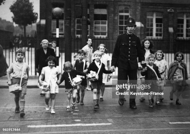 Un policier aident les enfants à traverser la rue, à Londres, Royaume-Uni le 20 septembre 1939.