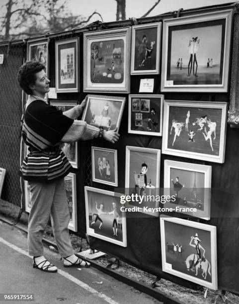 Jeune femme accrochant ses toiles sur son stand pendant l'exposition à Victoria Embankment à Londres, Royaume-Uni le 30 avril 1956.