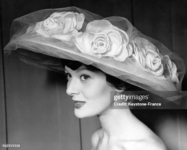 Mannequin présentant le modèle 'English rose' de Claude Saint-Cyr: un grand chapeau en soie rose ornée de roses, au Norman Hartnell's Salon à...