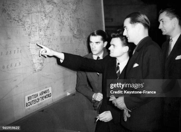 Quatre pilotes français en visite au siège de la BOAC regardent avec beaucoup d'intérêt la carte des vols des avions britanniques, à Londres,...