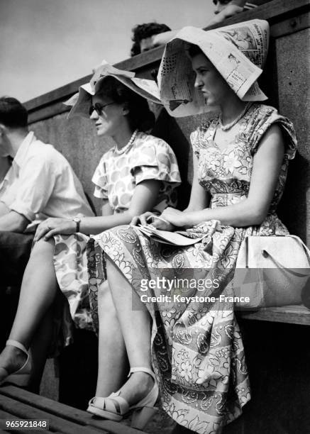 Pour se protéger du soleil, ces jeunes femmes ont fabriqué un chapeau avec leurs journeaux, à Wimbledon, Londres, Royaume-Uni le 28 mai 1949.